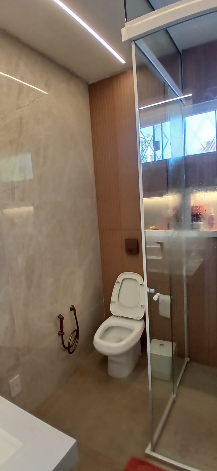 Banheiro pequeno recém-reformado com porcelanato claro, box de vidro temperado e bancada em quartzo branco
