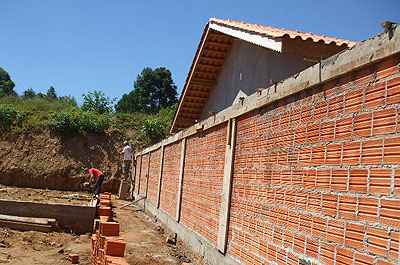 Muro de divisa em blocos de concreto rebocado entre dois terrenos residenciais